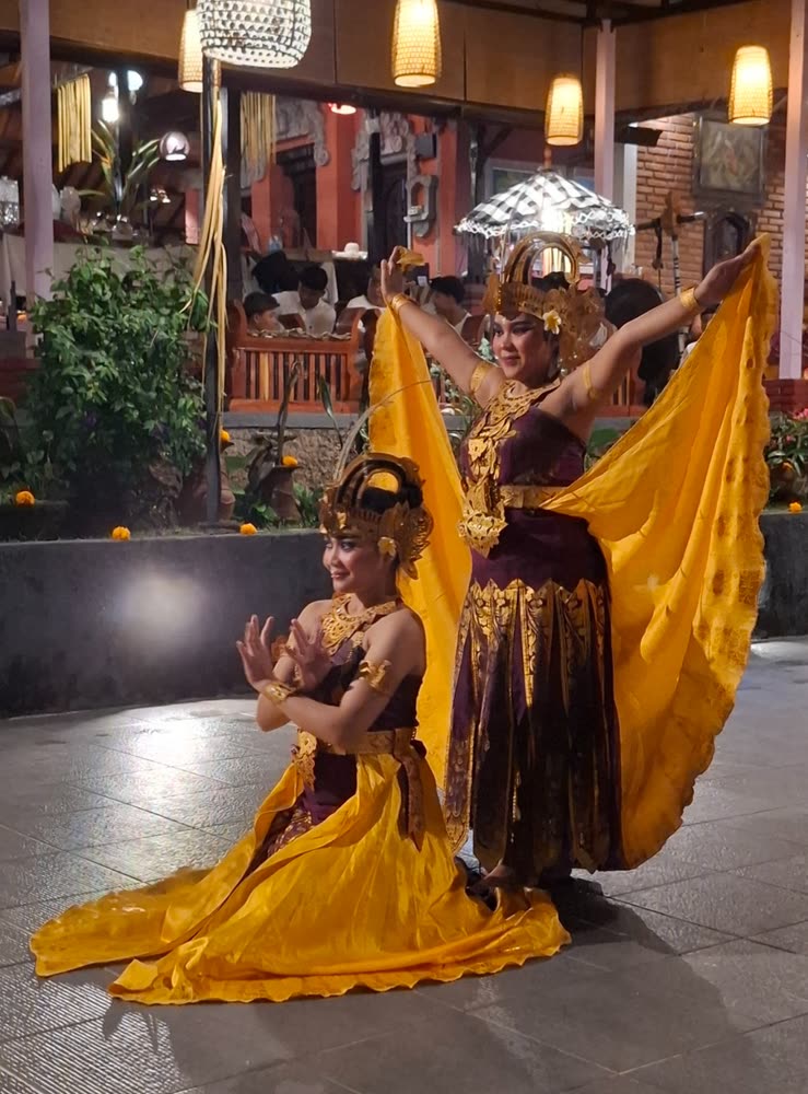 Balinese dancers in gold headdresses and yellow silk performing for the group in the evening