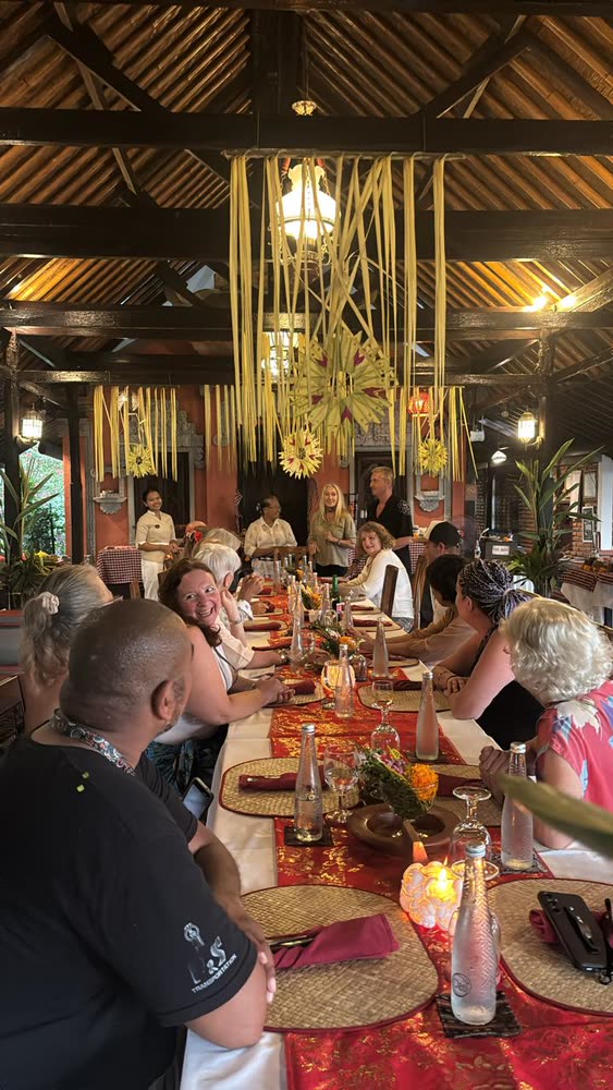 The group gathered at the long dinner table beneath woven palm-leaf decorations in the open pavilion