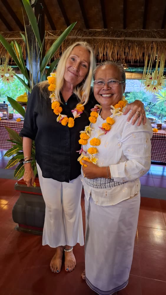 A retreat guest and a Balinese host wearing marigold garlands after the welcome ceremony