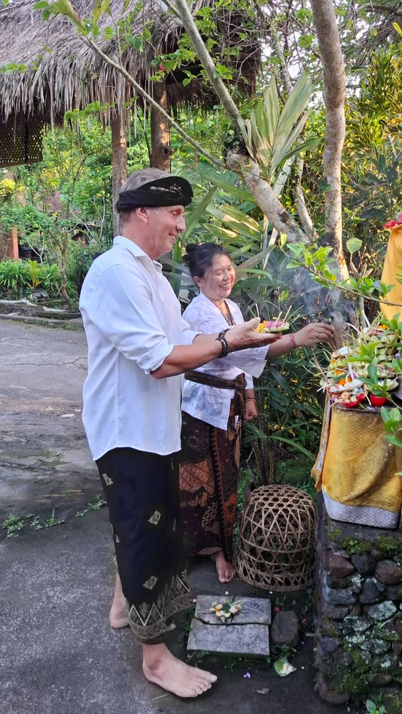 Ole Dammegard placing a canang sari offering at the villa shrine with a Balinese host