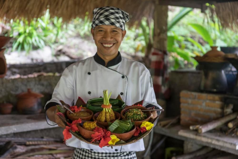 The retreat chef presenting a platter of organic Balinese dishes served in banana leaf