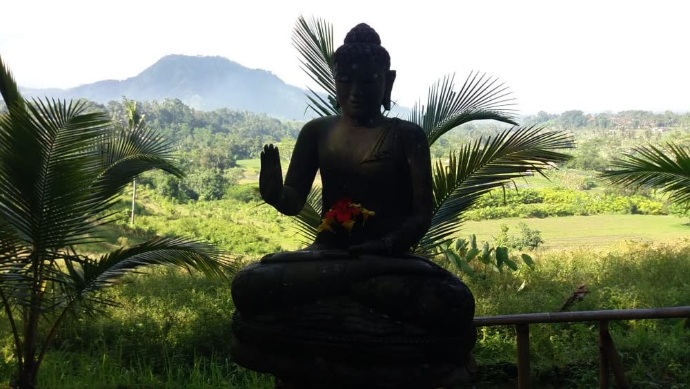 Stone Buddha overlooking the rice fields and mountains of East Bali at first light