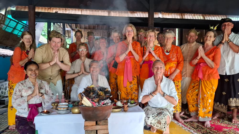 The retreat group in Balinese ceremonial dress, hands in prayer around the fire ceremony
